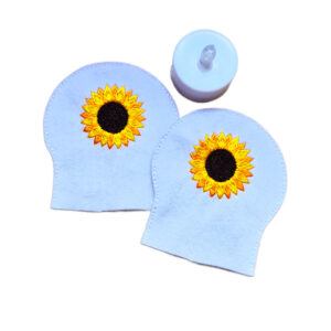 Two embroidered sunflower tealight covers made from white felt, shown with an LED tealight for display.