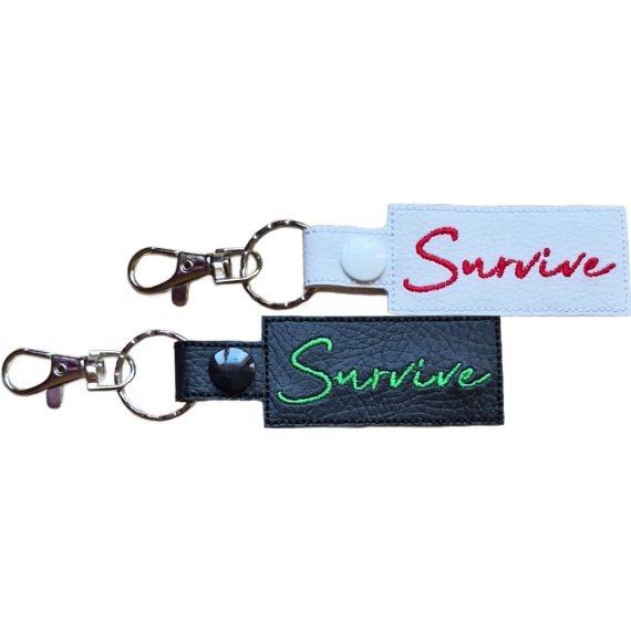 Embroidered Survive keyring in faux leather, with the word 'Survive' stitched on black and white backgrounds with sturdy metal hardware.