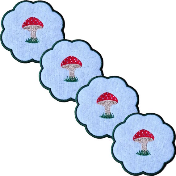 Set of four embroidered toadstool candle coasters with red stitched toadstools, grassy details, scalloped edging and matching woodland style.