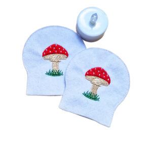 Set of two embroidered toadstool tealight covers made from soft felt, shown with an LED tealight for a cosy woodland inspired display.
