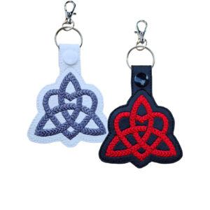 Black and white Trinity Heart Celtic Knot keyrings with embroidered knotwork designs and silver metal clasps.