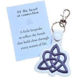 White Trinity Heart Celtic keyring with grey embroidered knot design, shown with a matching keepsake card about connection and lasting bonds.