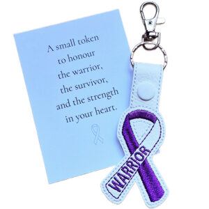 Embroidered Warrior awareness ribbon keyring made from faux leather, shown with a keepsake card featuring a message of strength, courage and support.