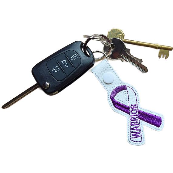 Embroidered Warrior awareness ribbon keyring attached to a set of keys, showing the white faux leather design with purple stitched ribbon detail and silver metal hardware.