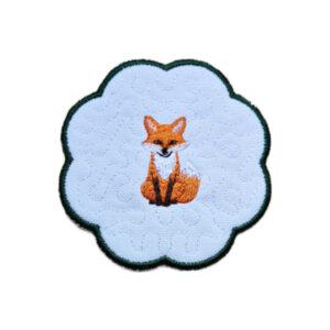 Embroidered woodland fox candle coaster with a sweet orange fox in the centre, soft textured background and dark green scalloped border.