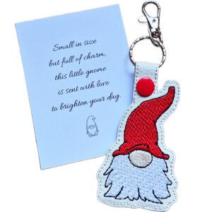 Embroidered woodland gnome keyring with a red hat and white beard, shown beside a matching keepsake card with a cheerful gnome gift message.