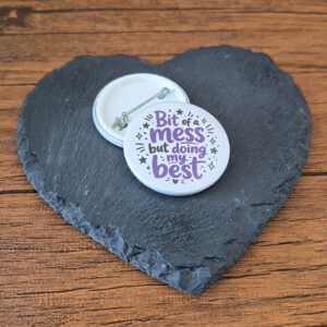 Funny positive badge design with the phrase 'Bit of a mess but doing my best' in playful lettering, decorated with small star and sparkle accents.