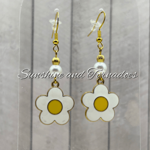 Handmade daisy drop earrings featuring white enamel flower charms with yellow centres, elegant pearl beads and gold-tone ear wires, creating lightweight floral jewellery perfect for spring and summer wear.