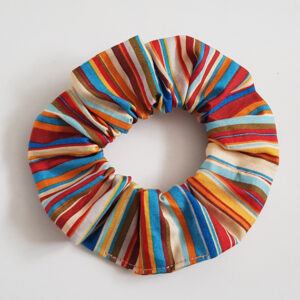 Earthy boho striped cotton scrunchie with teal, rust, mustard and cream stripes on a white background.