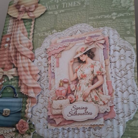 Fashion hemed greeting card for a female celebrate a birthday etc close up of a paper lace topper cream in colour and a small topper with a lady in a dress
