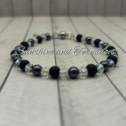 Handmade gemstone bracelet featuring matte black obsidian beads, polished hematite beads, sparkling Czech crystal beads and a detailed silver-tone cross charm on a secure clasp fastening.