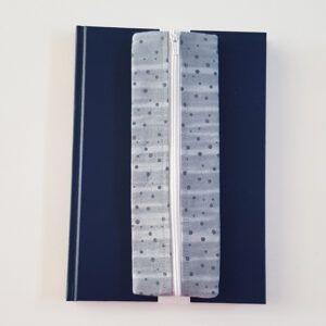Handmade A5 planner zipper pouch in grey spot print cotton fabric, shown fitted around a navy A5 notebook with a white zip and elastic strap, holding pens and small stationery items.