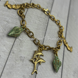 Image shows a handmade gold bracelet featuring Mermaid and Sea Shell charms.