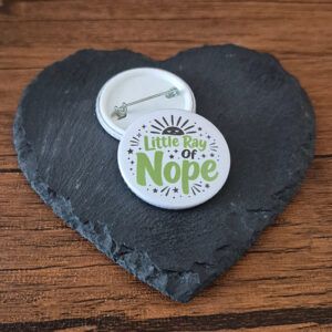 Funny sarcastic badge design with the phrase 'Little ray of nope' in playful lettering, decorated with small sparkle and sunburst accents.