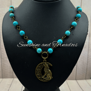 Photograph depicting handmade necklace of Turquoise beads with a Bronze Wolf charm.