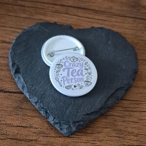 Crazy Tea Person funny tea lover badge with playful lettering and small tea cup accents, available as a badge, magnet or keyring.