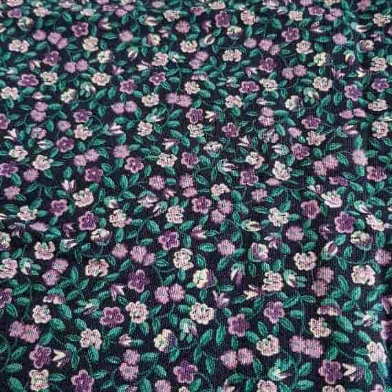 Purple and cream ditsy floral fabric with green leaves on a dark navy background.