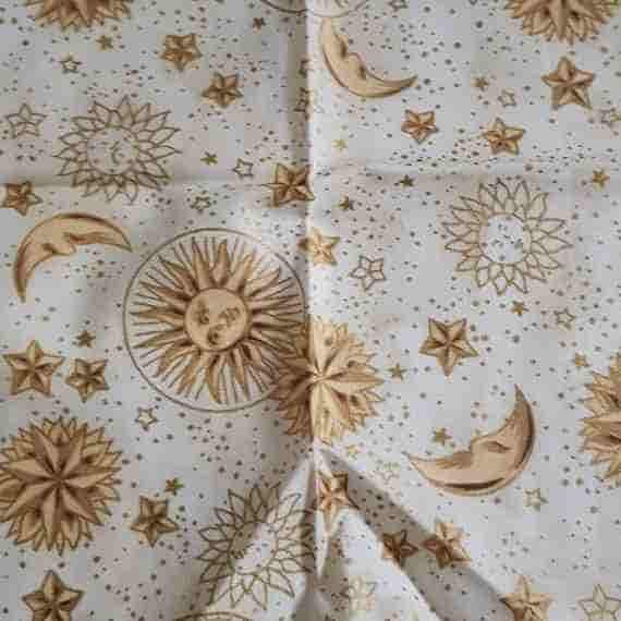 Cream celestial fabric with gold suns, moons, stars and scattered stardust details.