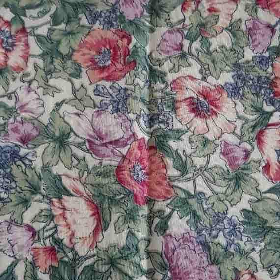 Cream fabric with red, pink and purple poppies, blue floral accents and soft green leafy details.