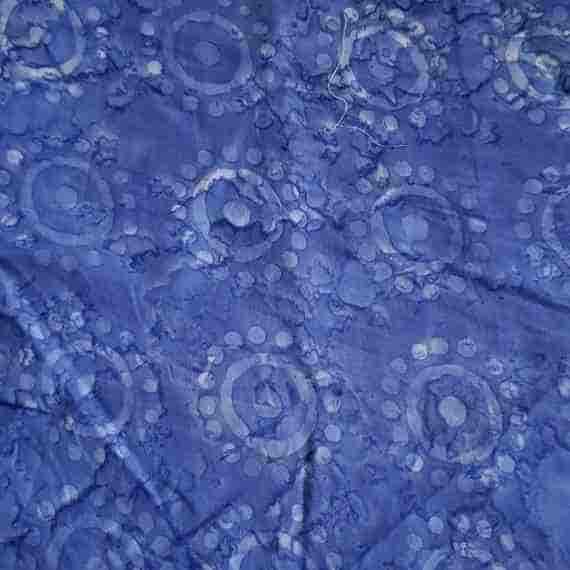 Blue batik fabric with abstract sunburst circles, dotted details and a textured hand-dyed style pattern.