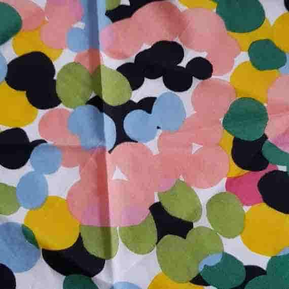 Bright multicoloured spot fabric with large overlapping circles in pink, green, blue, yellow and black on white.