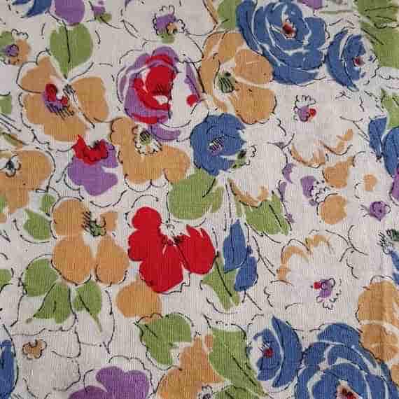 Vintage floral fabric with blue, red, orange and purple flowers, green leaves and black sketch-style details on cream.
