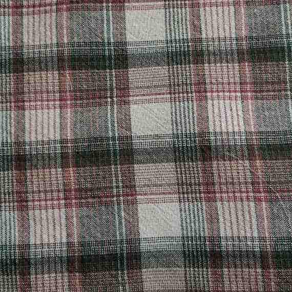 Rustic tartan fabric with cream, brown, burgundy and dark green checks in a classic woven plaid pattern.