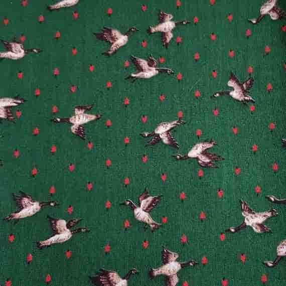 Green wildlife fabric with flying geese, tiny red hearts and a charming countryside-inspired repeating pattern.