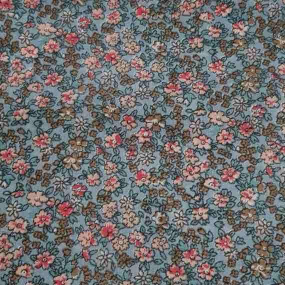 Pale blue ditsy floral fabric with tiny pink, cream and brown flowers, leafy details and a vintage-style repeating pattern.