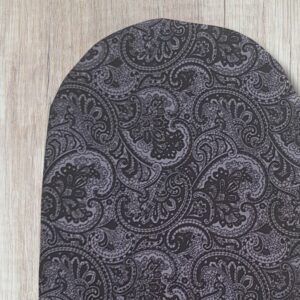 Handmade grey paisley stoma bag cover with black and grey vintage-style swirling fabric, shown close up on a wooden background.