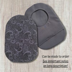 Two handmade stoma bag covers on a wooden background, showing a grey paisley patterned front cover and a plain grey reverse cover with an opening, with text saying can be made to order.